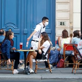 A waiter wearing a face mask serves clients while people eat and have drinks on the terrace of the cafe-restaurant  in Paris on June 2, 2020, as cafes and restaurants reopen in France with the easing of lockdown mesures taken to curb the spread of the COVID-19 pandemic, caused by the novel coronavirus. French cafes and restaurants reopened their doors on June 2 as the country took its latest step out of coronavirus lockdown, with clients seizing the chance to bask on sunny terraces after 10 weeks of closures to fight the outbreak.



 (Photo by Mehdi Taamallah/NurPhoto via Getty Images)