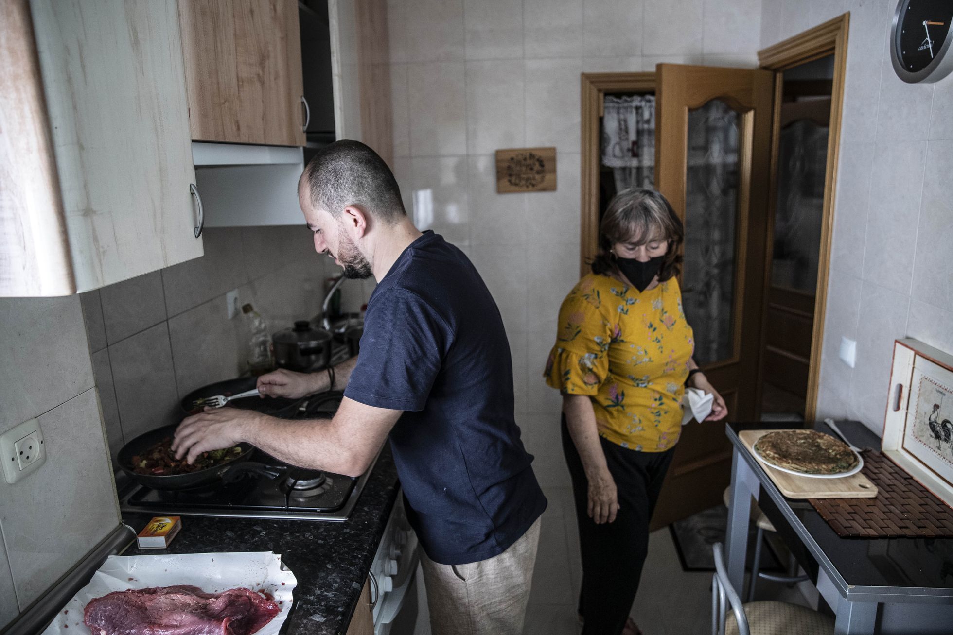 Víctor Hernán prepara la comida con su madre, Marta Giralda, en el piso de Alcorcón (Madrid) en el que vive con su familia. 