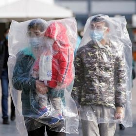 Passengers wearing masks and covered with plastic bags walk outside the Shanghai railway station in Shanghai, China, as the country is hit by an outbreak of a new coronavirus, February 9, 2020. REUTERS/Aly Song