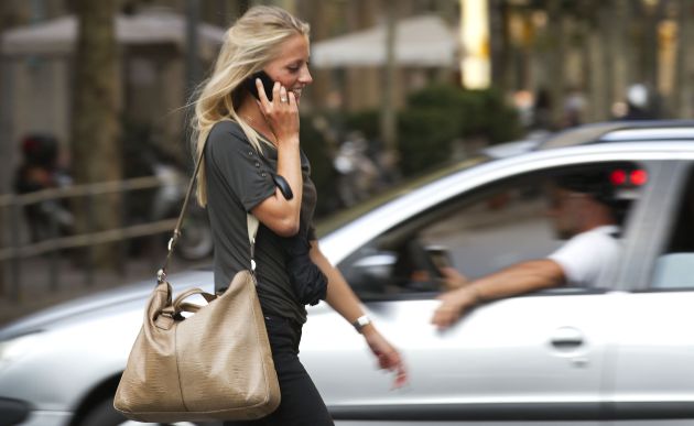 Una mujer camina hablando por su tel&eacute;fono m&oacute;vil en Barcelona.