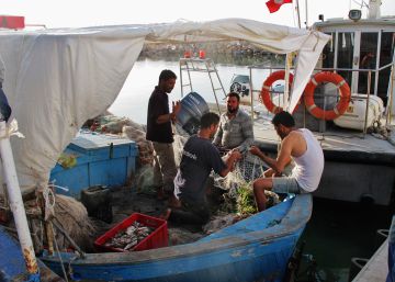 Cuatro pescadores recosen las redes antes de salir en alta mar en una de las barcas típicas de Katef, de tamaño medio.