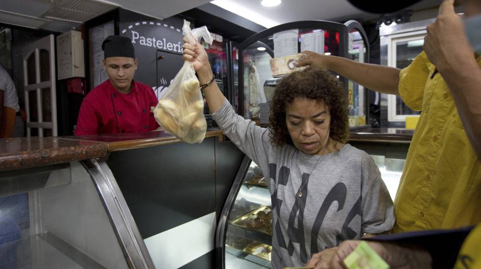 Clientes compran pan subsidiado en una pastelería de Caracas.