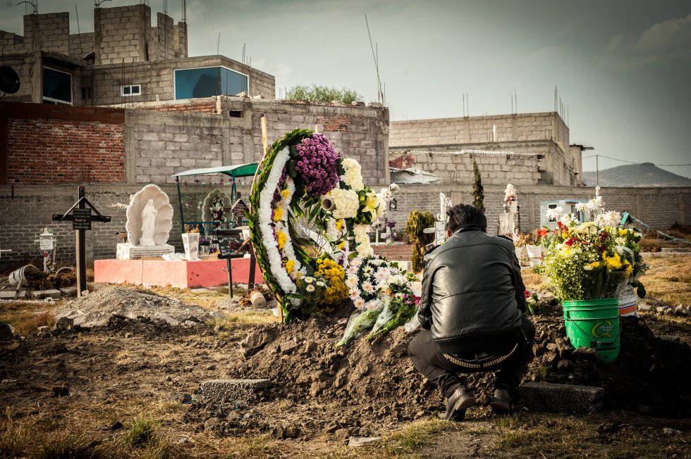 Un hombre visita la tumba de una mujer asesinada en Ecatepec.