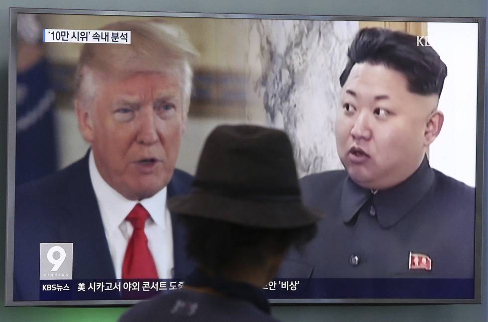 Un hombre mira una televisión en la que aparecen Kim Jong Un y Donald Trump.