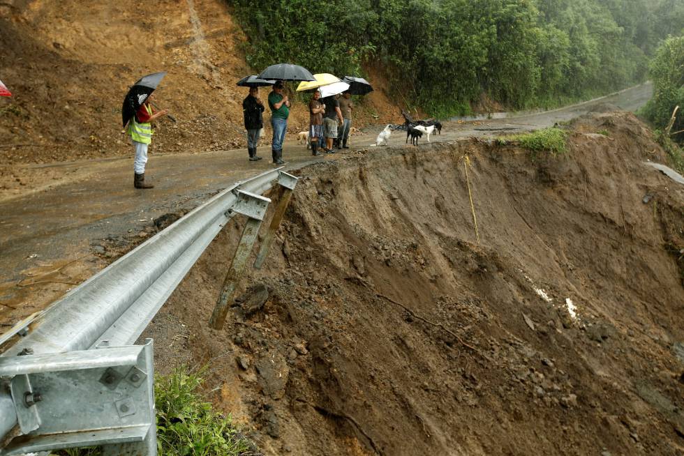 Algunas personas miran una carretera parcialmente destrozada por las lluvias en Costa Rica.