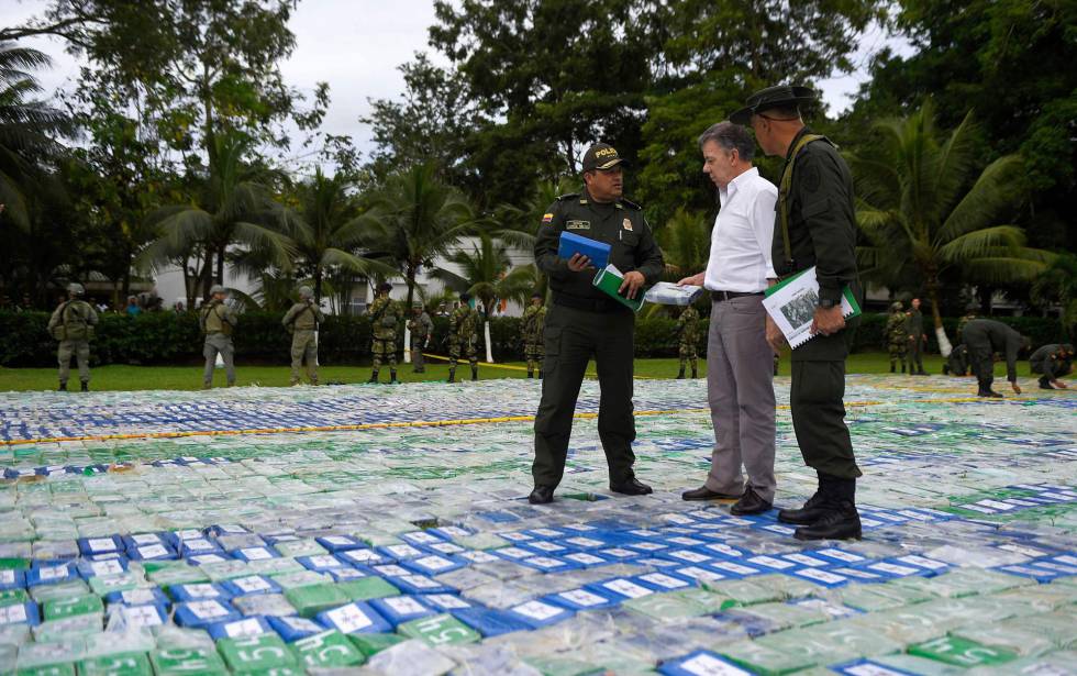 El presidente de Colombia, Juan Manuel Santos, y dos agentes sobre las más de 12 toneladas de cocaí­na incautada. rn rn rn 