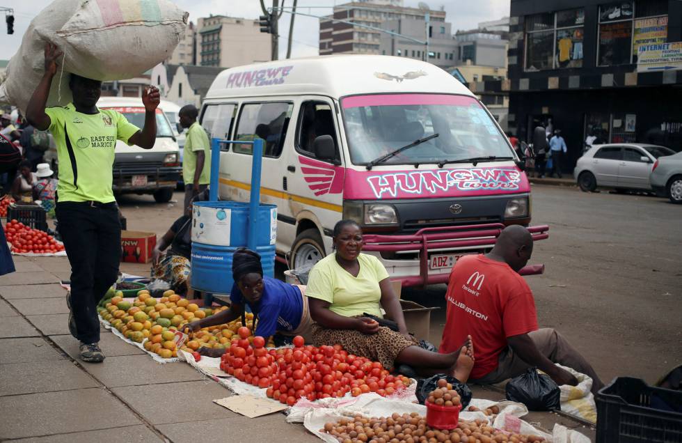 Varias personas venden fruta y verdura ayer en una calle de Harare. 