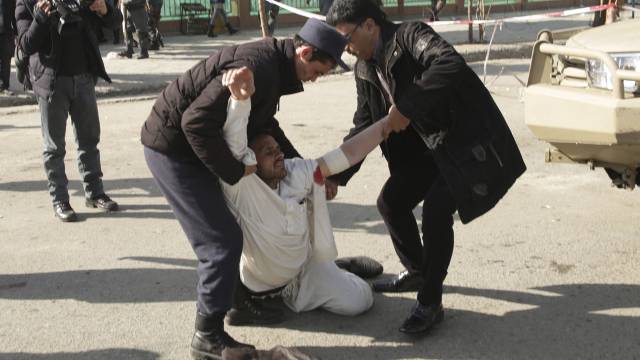 Dos hombres ayudan a un herido en el atentado de Kabul.