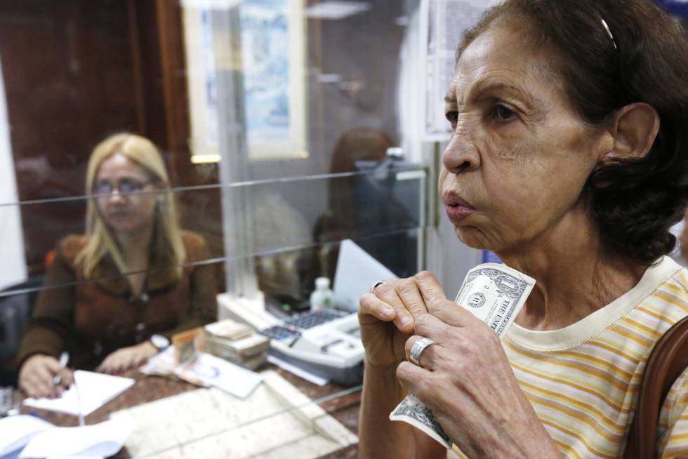 Una mujer venezolana porta billetes de un dólar en Caracas.