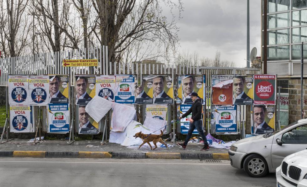 Un vecino de Pomigliano D'Arco pasea delante de los carteles electorales.