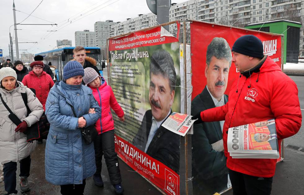 Militante do Partido Comunista da Rússia distribui panfleto junto a cartazes da campanha eleitoral do candidato comunista, na última terça-feira.