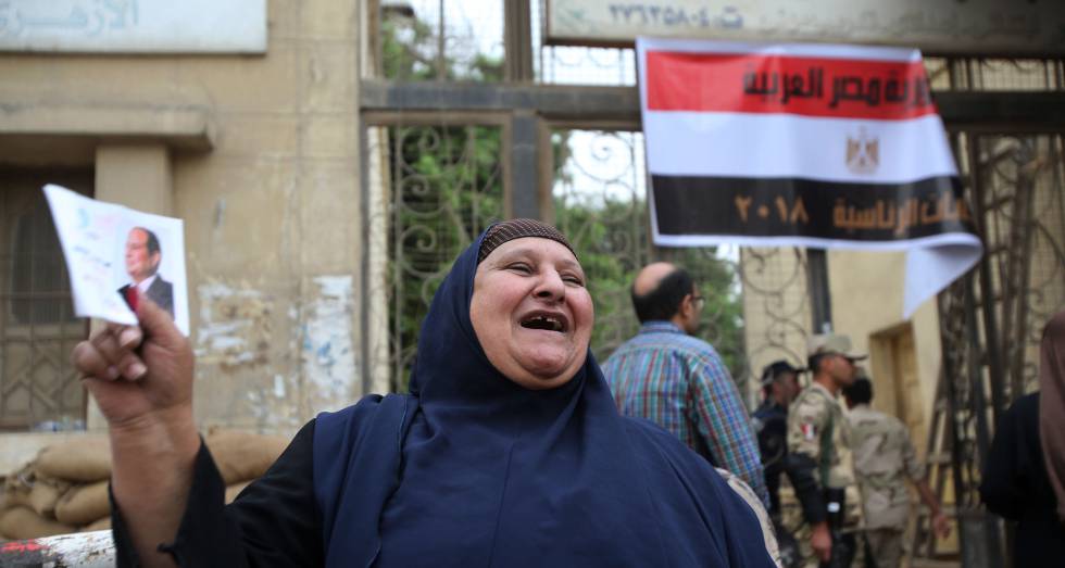 Una egipcie sostiene una foto de AbdelfatÃ¡ al Sisi en la entrada de un colegio electoral en El Cairo, este miÃ©rcoles.
