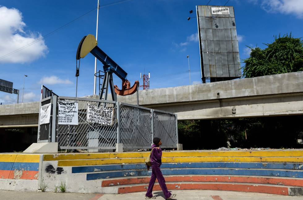Una mujer camina en una plaza con una bomba de aceite en Caracas.