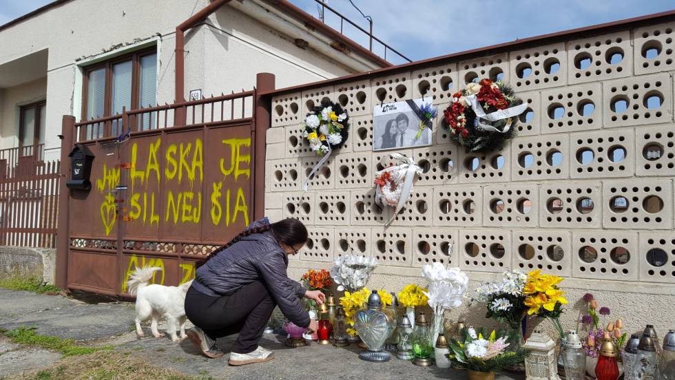 La señora Regina coloca las velas y las flores que los ciudadanos han dejado a las puertas de la casa de Kuciak y Kusnirova, en Velka Maca, el jueves.