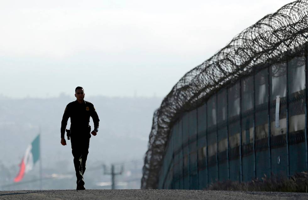 Un agente de la policÃ­a de fronteras, junto a la valla en San Diego. 