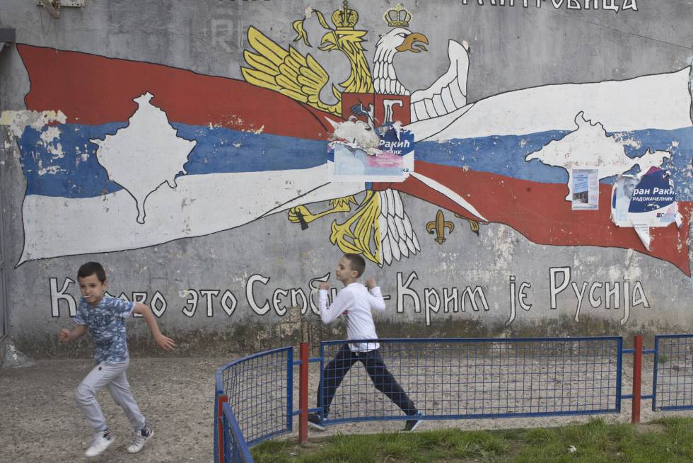 Niños jugando delante de un mural frente a símbolos serbios y rusos en el norte de Mitrovica, la zona en la que viven los serbios. El sur es la parte en la que viven los albanokosovares.