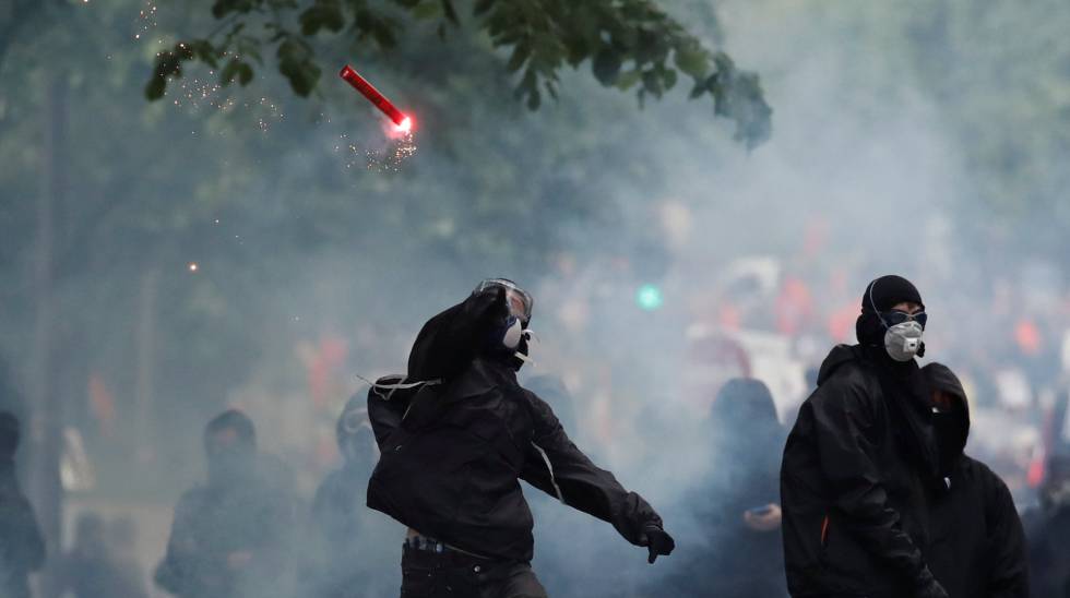 Unos encapuchados lanzan una bengala contra las fuerzas de seguridad, este martes en París.