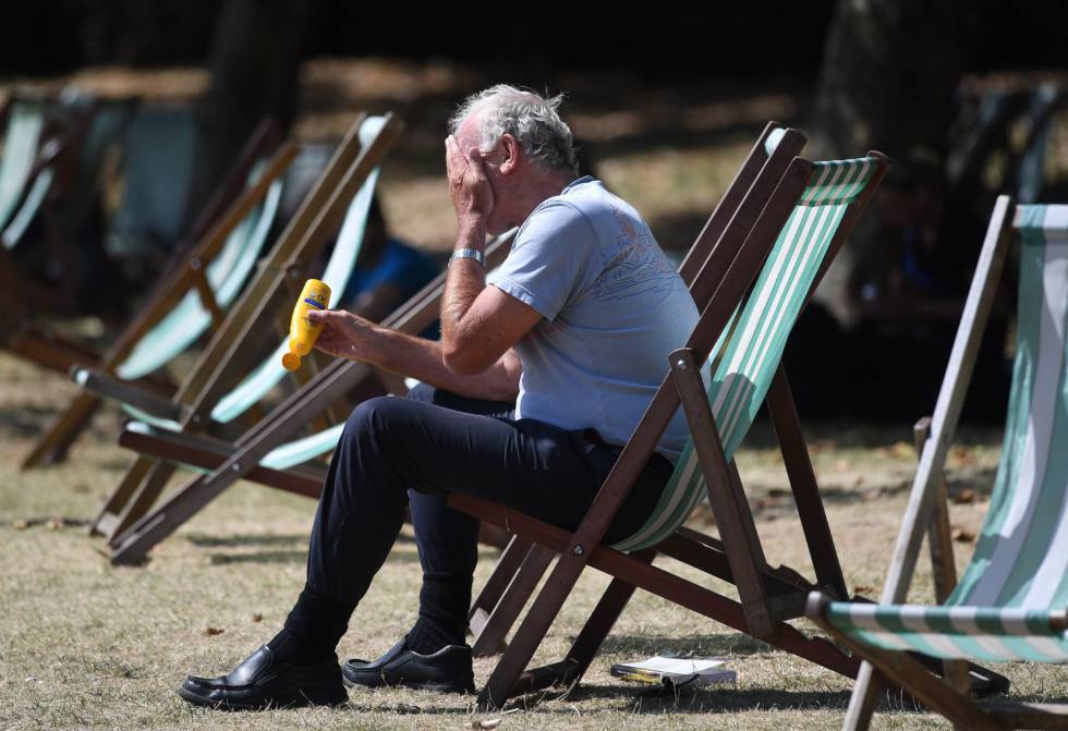 Un hombre se pone crema solar en el Green Park de Londres, Reino Unido.