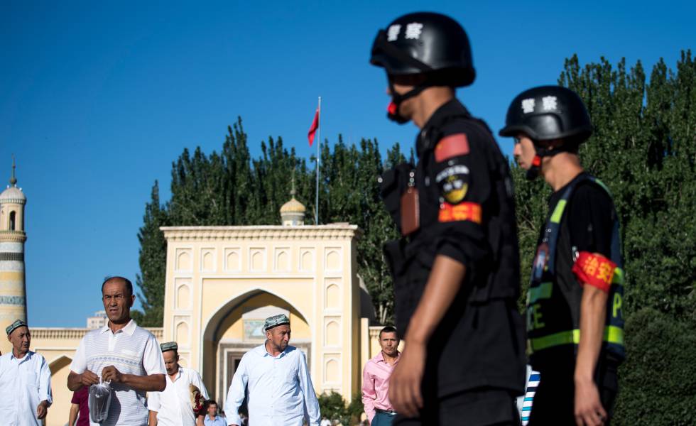 Unos policÃ­as chinos vigilan la salida de unos uigures de una mezquita, en 2017 en Kashgar.