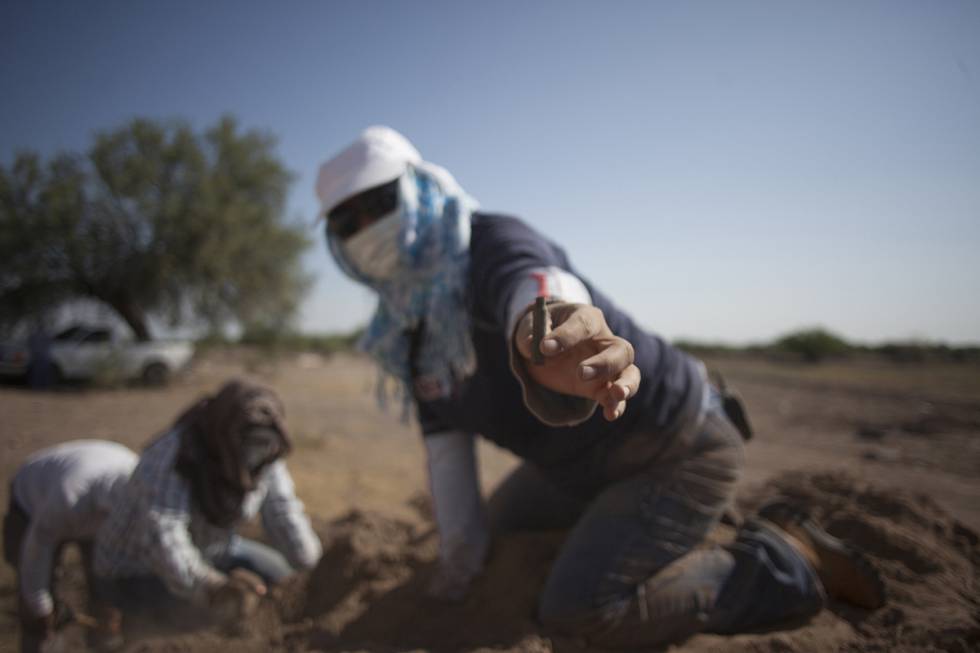 Una mujer muestra un casquillo encontrado en una fosa clandestina en Coahuila.