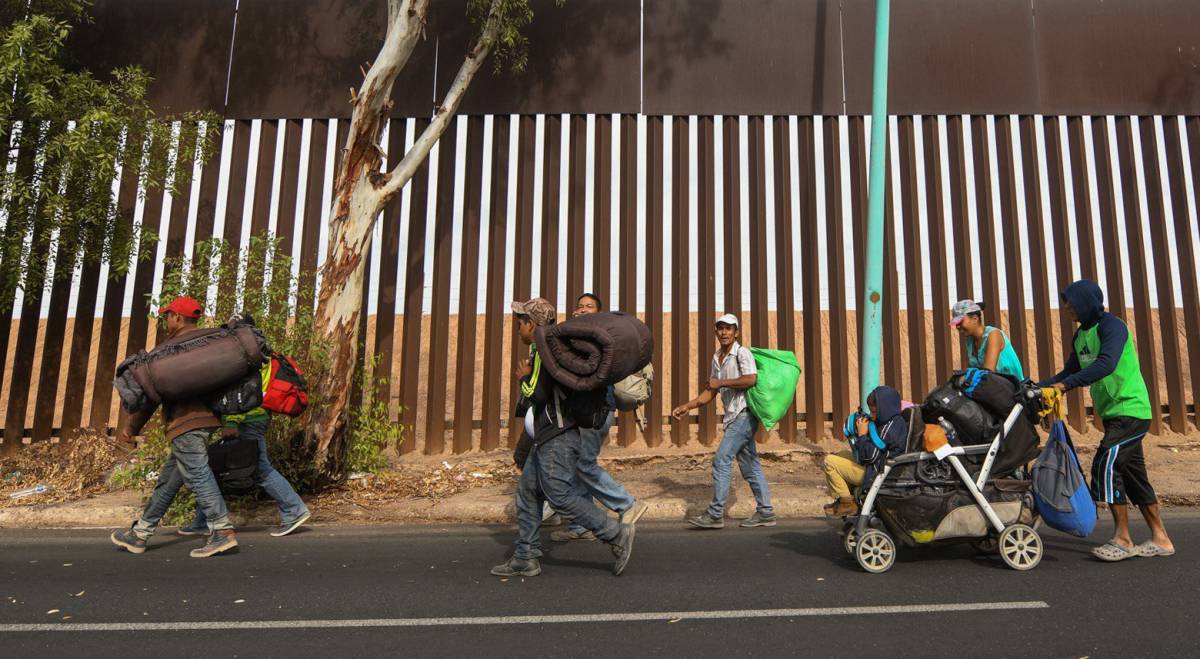 Decenas de migrantes centroamericanos caminan este martes por la valla fronteriza de Mexicali (México).