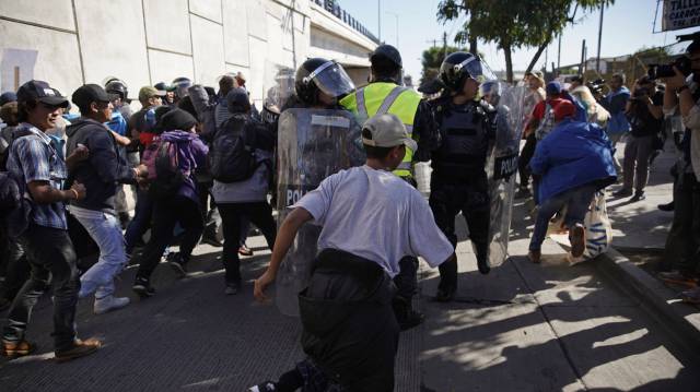Migrantes rompen el cerco policial en Tijuana, México.