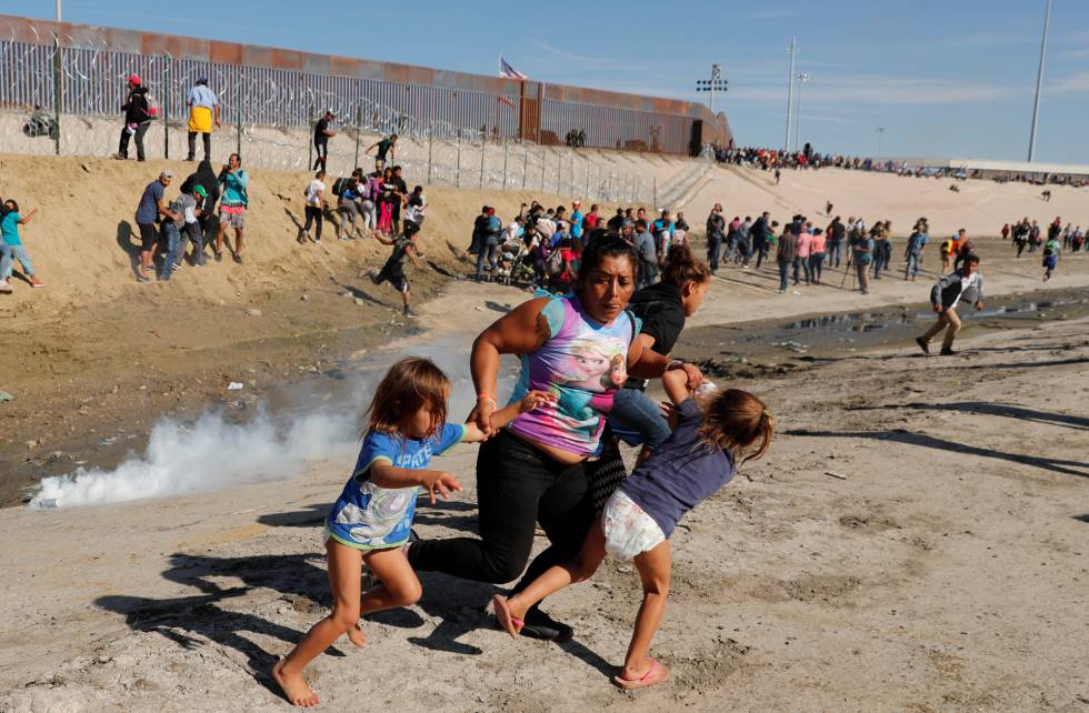 Una familia de migrantes escapa del lanzamiento de gases lacrimógenos en Tijuana.