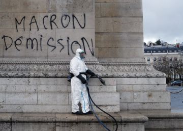 Un trabajador junto a una pintada contra el presidente Macron, este domingo en el Arco del Triunfo (París).