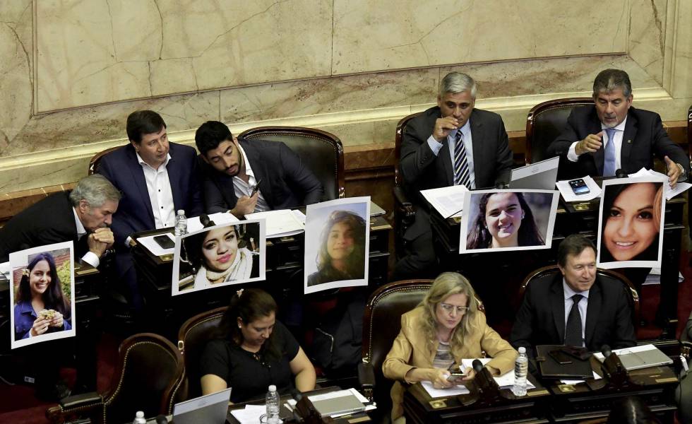 Diputados argentinos muestran fotos de mujeres víctimas de feminicidas durante la sesión del martes 18 de diciembre. 