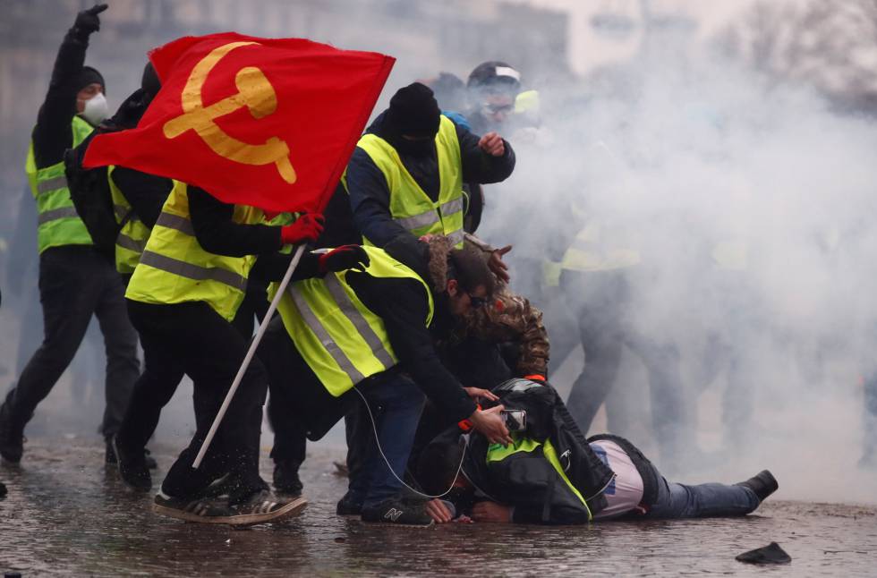 Unos 'chalecos amarillos' ayudan a un herido por el cañón de agua durante la protesta, cerca del Arco del Triunfo. 