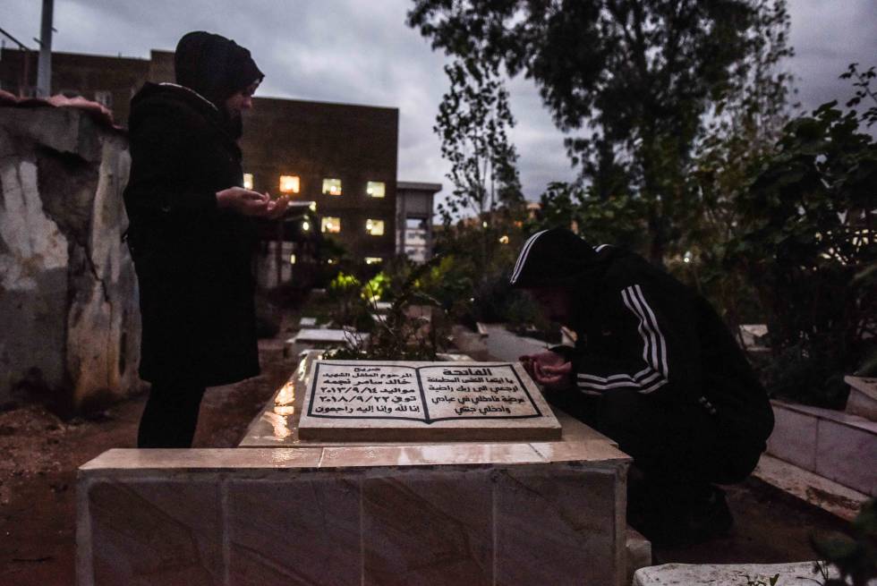 Nivine (izq.) y Samer (dch.) Najme rezan frente a la tumba de su hijo Jaled en el cementerio de los mártires en Trípoli