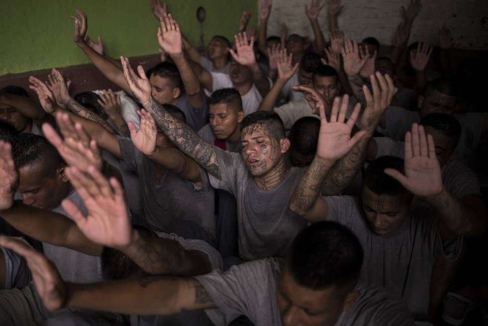 Antiguos pandilleros, recluidos en la cárcel de Gotera, levantan las manos durante el servicio religioso.