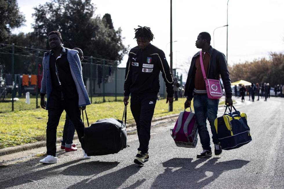 Tres migrantes se marchan del centro de acogida de Castelnuovo con sus maletas a cuestas.