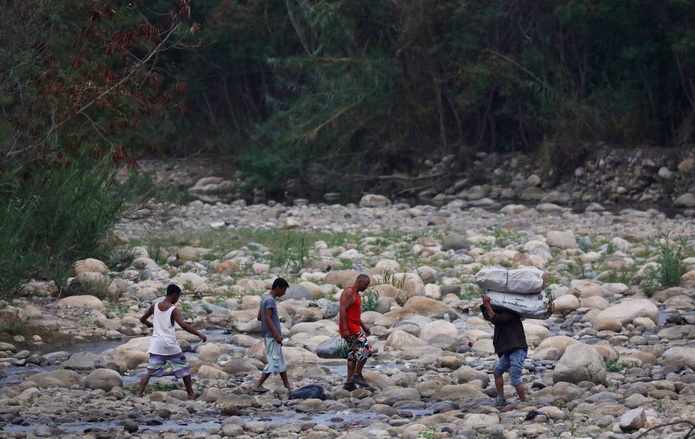 Un grupo de personas cruza el río Táchira, en las afueras de Cúcuta.