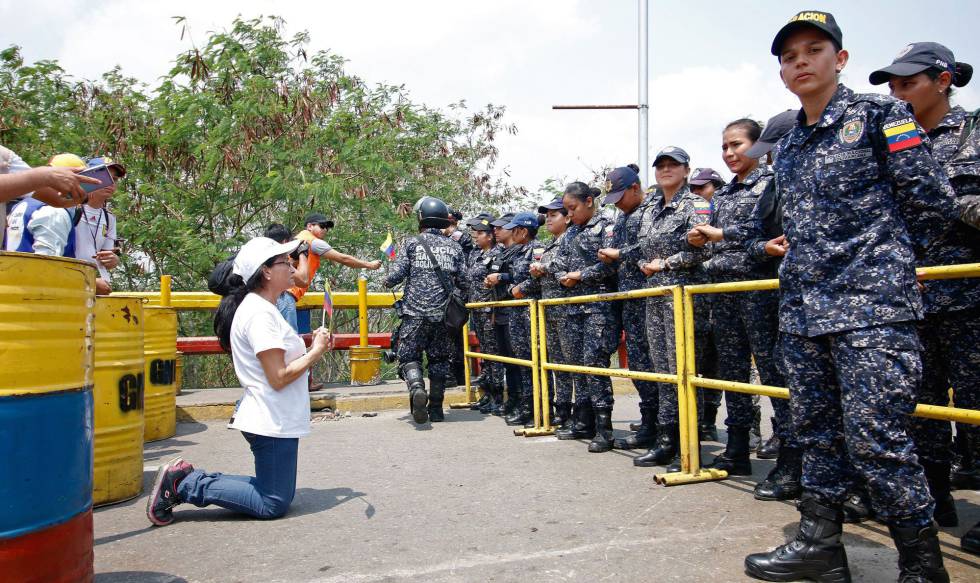 Una seguidora de Juan Guaidó se arrodilla frente a agentes de la Guardia Nacional Bolivariana.