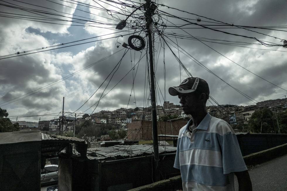 Um homem caminha em frente a uma instalaÃ§Ã£o elÃ©trica improvisada no bairro de Petares, um dos mais pobres de Caracas