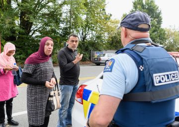Feligreses preguntan a un policía frente a la mezquita Al Noor después del atentado en Christchurch. 