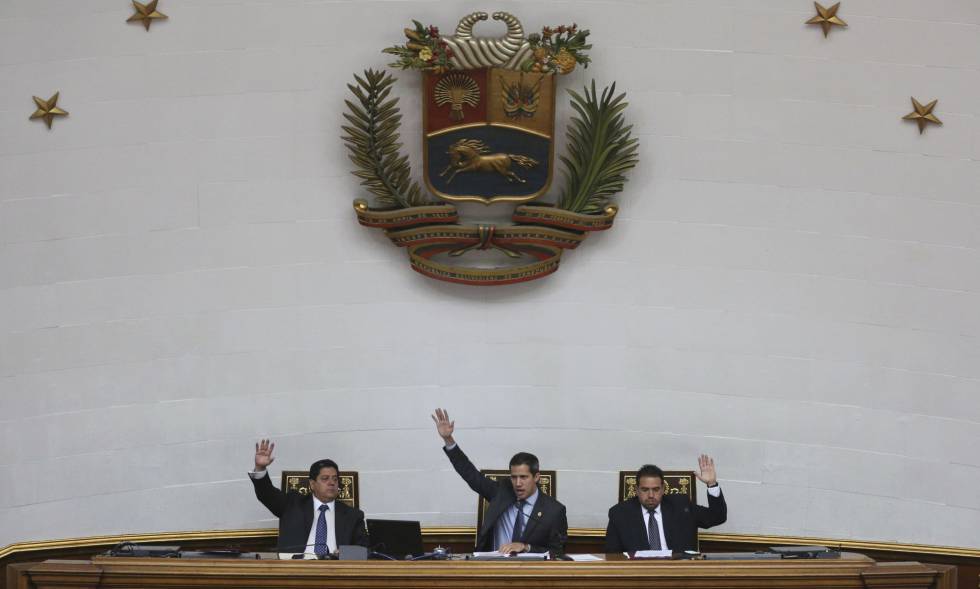 Juan Guaidó (centro) alzan sus manos en una sesión de la Asamblea Nacional venezolana.