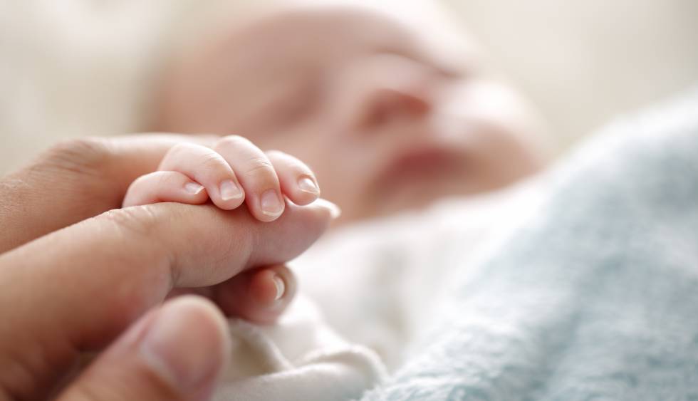 Un bebé agarra la mano de su padre.