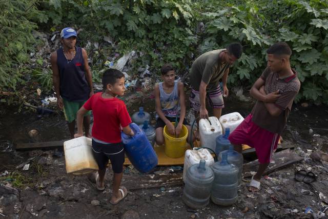Un grupo de jóvenes se abastece de agua en un riachuelo formado por una tubería rota, el pasado viernes en Maracaibo. 