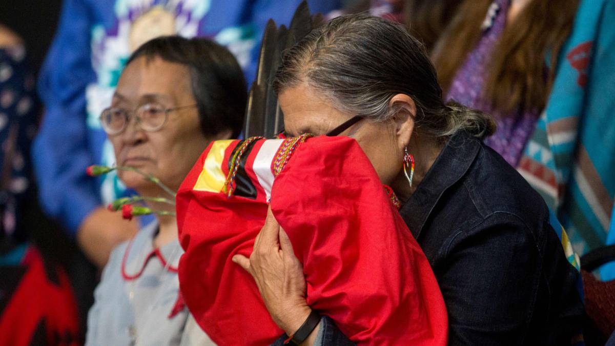 Una anciana indígena canadiense sostiene una copia del informe final sobre el genocidio que ha sufrido su pueblo, el tres de junio en Quebec.  