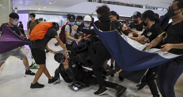 Unos manifestantes golpean a un policía, este domingo en Hong Kong.