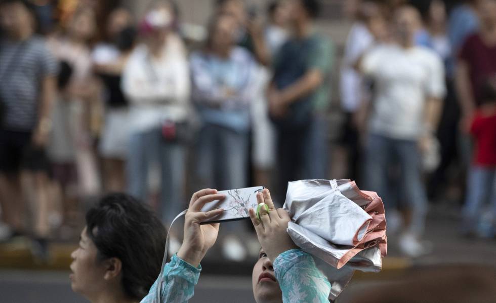 Una mujer toma una foto al Peace Hotel mientras un grupo espera la llegada de la delegaciÃ³n estadounidense en el diÃ¡logo comercial, este martes en ShanghÃ¡i.