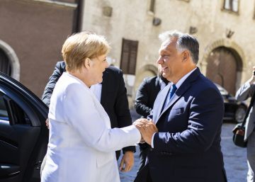 In this handout photo provided by the Hungarian Prime Minister's Press Office Hungarian Prime Minister Viktor Orban, right, welcomes German Chancellor Angela Merkel in Sopron, Hungary, Monday, Aug. 2019. Merkel arrived for the 30th anniversary of the beginning of the dismantling of the iron curtain between Hungary and Austria. (Balazs SzecsodiHungarian Prime Minister's Press OfficeMTI via AP)