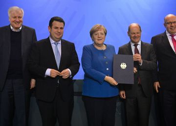 La canciller alemana, Angela Merkel, muestra el documento firmado por varios ministros, empresarios y sindicatos para acelerar la entrada de trabajadores cualificados en Alemania, tras la celebración de una cumbre sobre el tema en Berlín. 