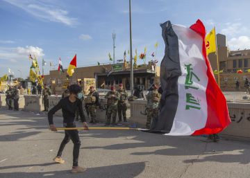 Un hombre ondea una bandera iraquí ante soldados estadounidenses desplegados frente a la Embajada.