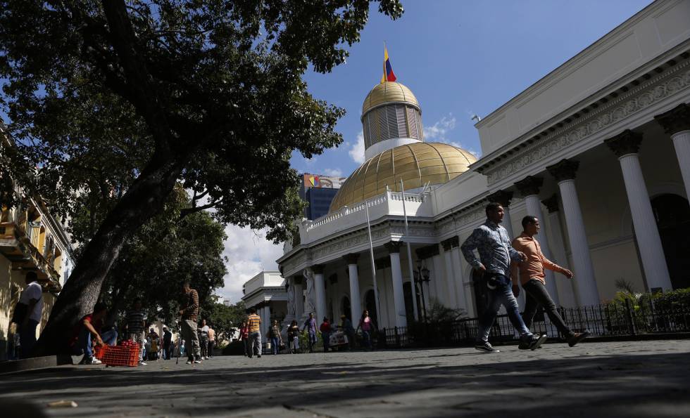 Dos personas caminan afuera de la Asamblea Nacional de Venezuela.