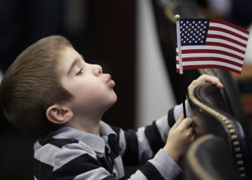 Un niño juega con una bandera de EE UU durante la ceremonia de naturalización de su madre. 