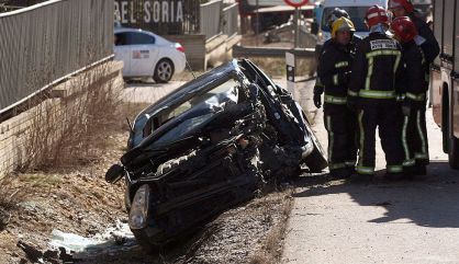 Un equipo de bomberos junto a un vehículo siniestrado en Soria.