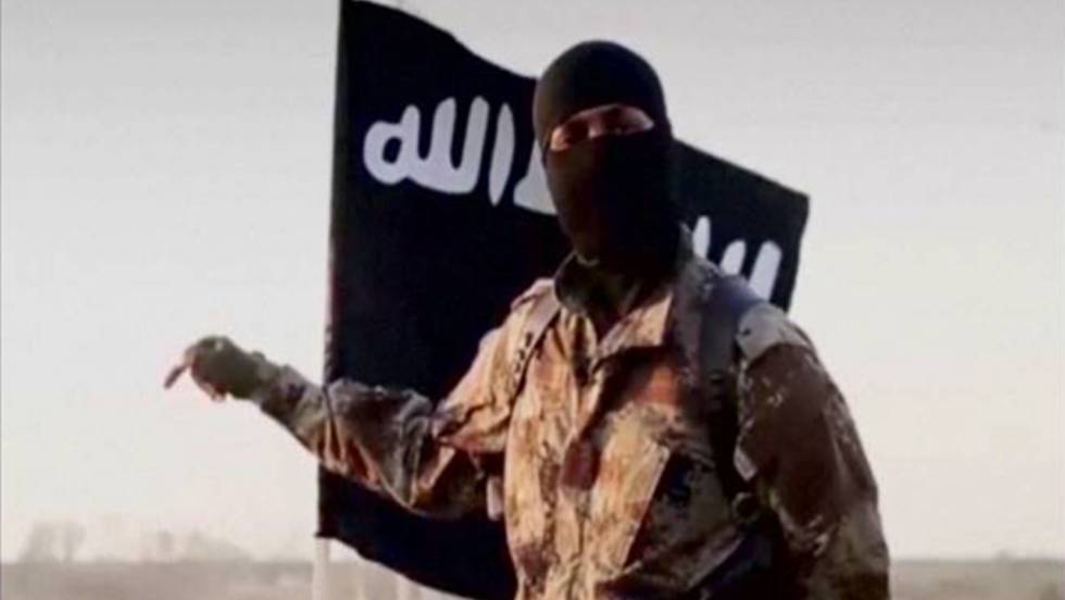 Un yihadista delante de la bandera del Estado Islámico (ISIS)